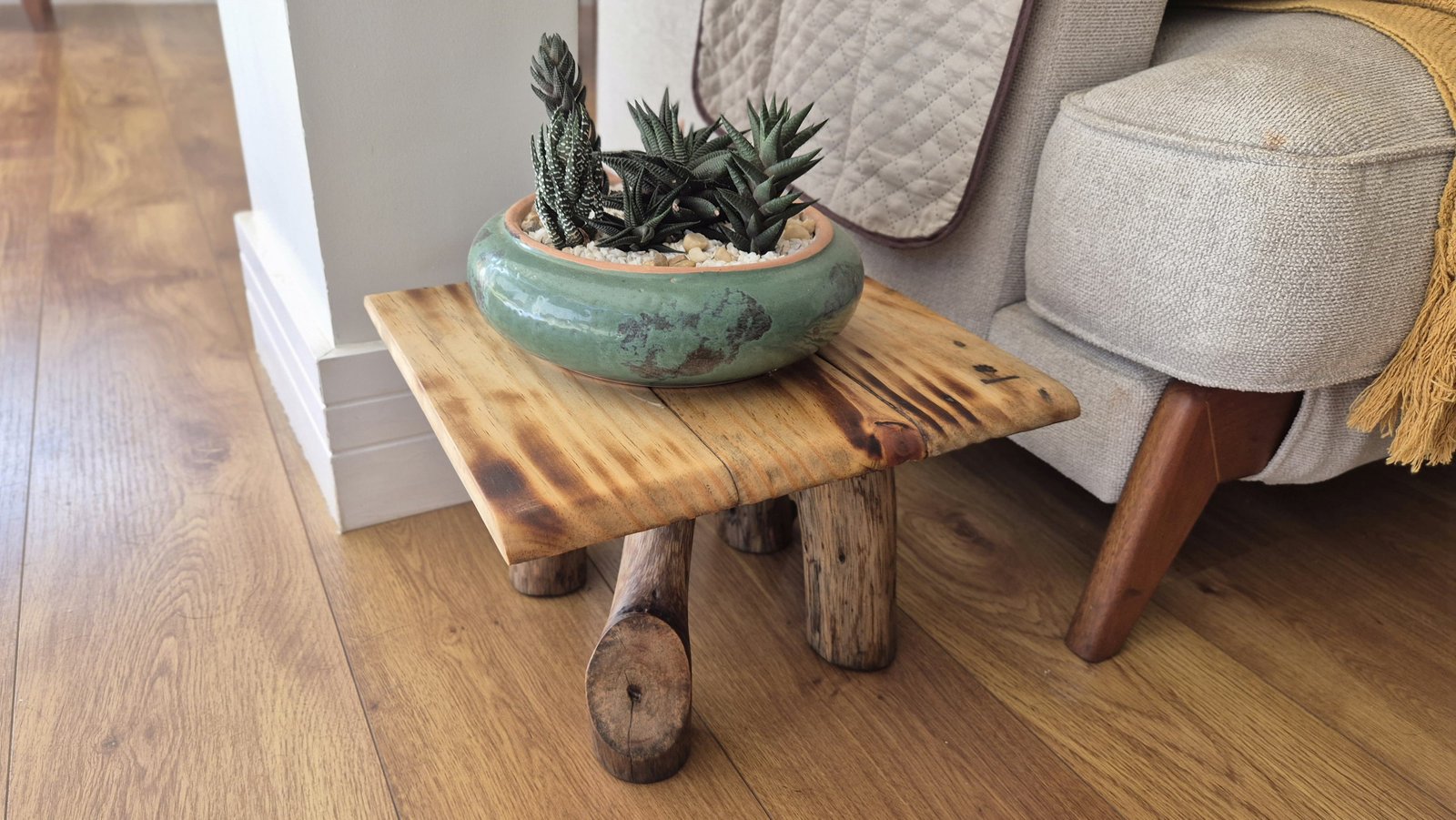 Móvel feito por Marcelo Nisida: mesa lateral de madeira com pés de galhos e vaso de suculentas